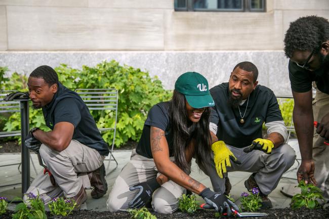 Four University City District employees planting flowers alongside a public plaza.