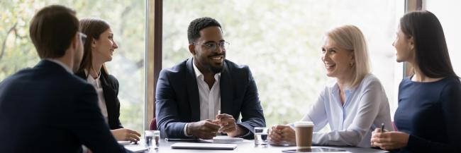 A businessman sitting at a table with four colleagues